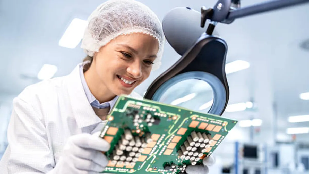 Factory worker controling quality of electronic parts for automobile industry.