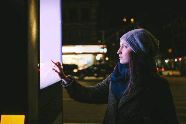 Young woman using interactive touch screen city display to check for information, Cidade de Nova York, EUA.