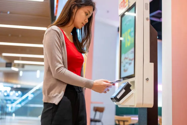 A Young Asian Woman At Making A Mobile Payment At Self Service Kiosk