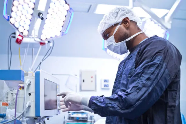 Side View Of Male Surgeon Using Monitoring Equipment In Operating Room