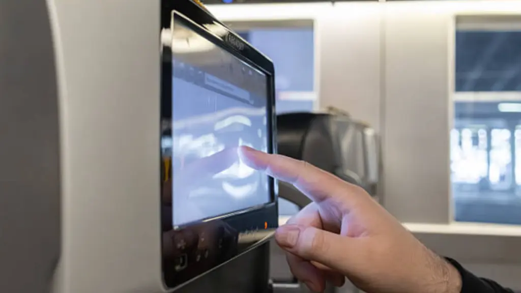 A Passenger Hand Touches The Seat Back Entertainment Touchscreen On A Modern Train