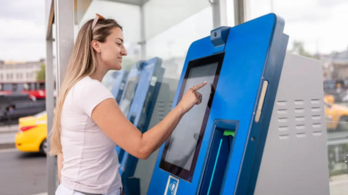 A Young Woman Interacts With A Touchscreen On A Blue Ticket Kiosk