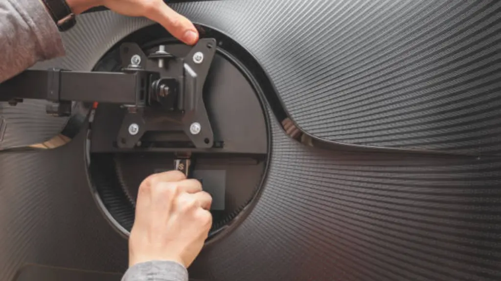 Hands Of A Young Caucasian Guy Manually Twists A Nut On A Bracket While Installing On A Computer Monitor