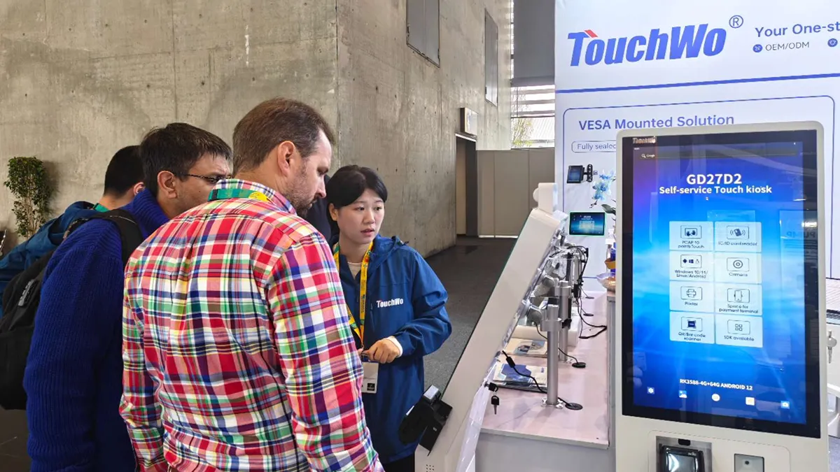 A Staff Member Presenting A Touch Kiosk To Trade Show Visitors