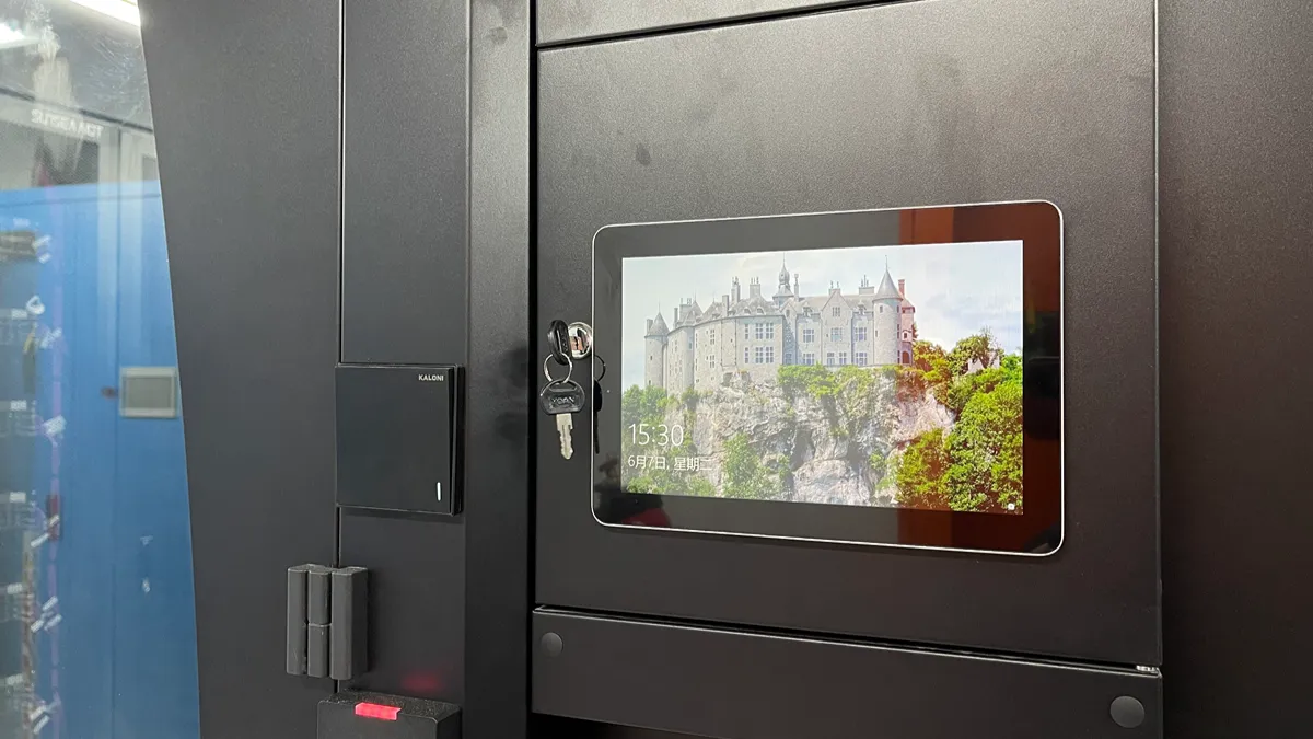 A touch display panel fitted into a black cabinet door with keys left in the lock beside it