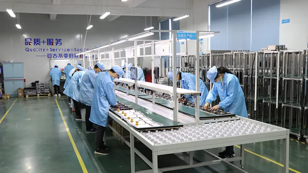 Workers Assembling Electronic Display Panels Along A Factory Production Line